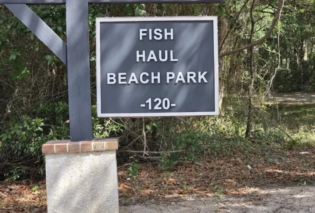 Fish Haul Beach Park entrance sign surrounded by trees